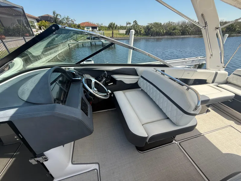 Slide: The Image of 2020 Regal 29 OBX boat interior with steering wheel and seating by the water. - 23