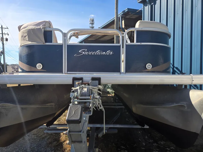 Slide: The Image of 2014 Sweetwater 2086 pontoon boat on trailer, parked near blue building. - 2