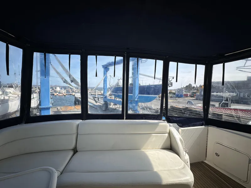 Slide: The Image of Interior view of 2002 Sea Ray 510 Sundancer yacht with white seating and marina backdrop. - 21