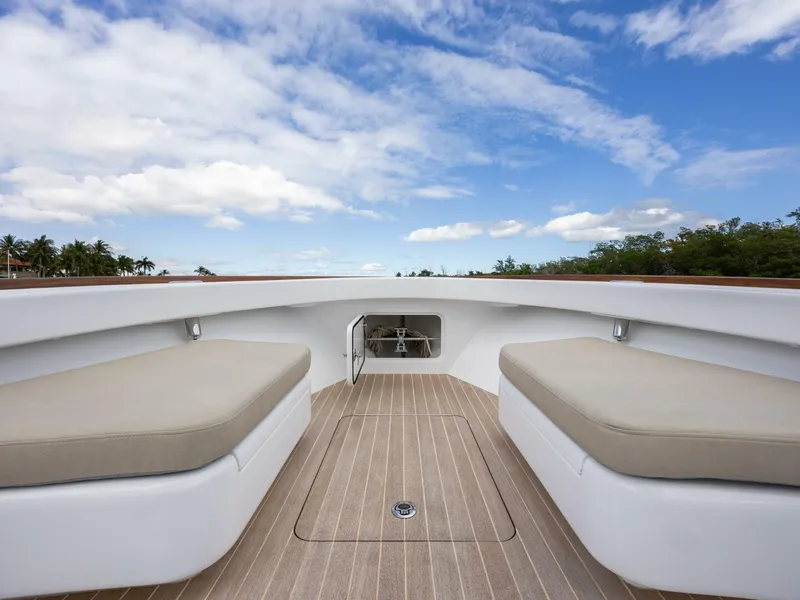 Slide: The Image of 2024 Xcelerator Boatworks 26 interior with cushioned seating and wooden deck under blue sky. - 11