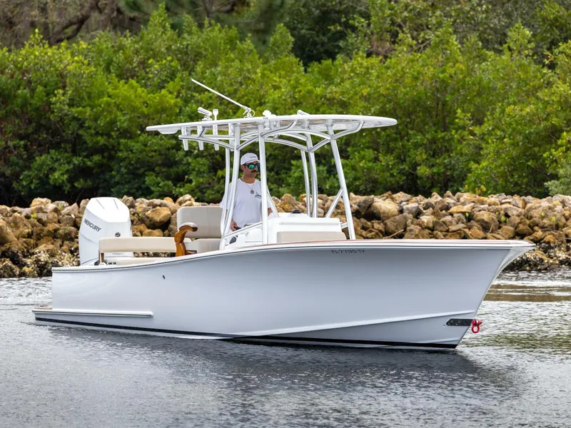 Slide: The Image of 2024 Xcelerator Boatworks 26 in water, sleek design, white hull, lush greenery background. - 2