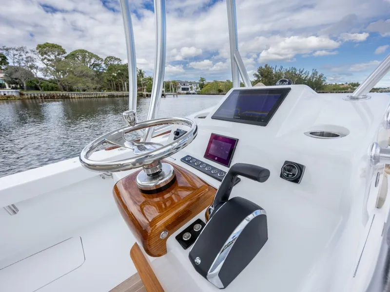 Slide: The Image of 2024 Xcelerator Boatworks 26 helm with modern controls and scenic waterway view. - 24