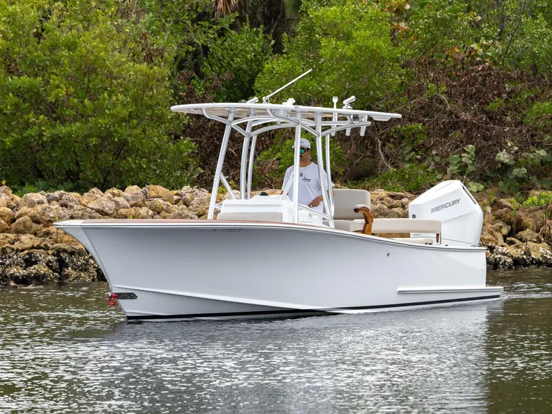 Slide: The Image of 2024 Xcelerator Boatworks 26 cruising on a calm waterway, surrounded by lush greenery. - 3