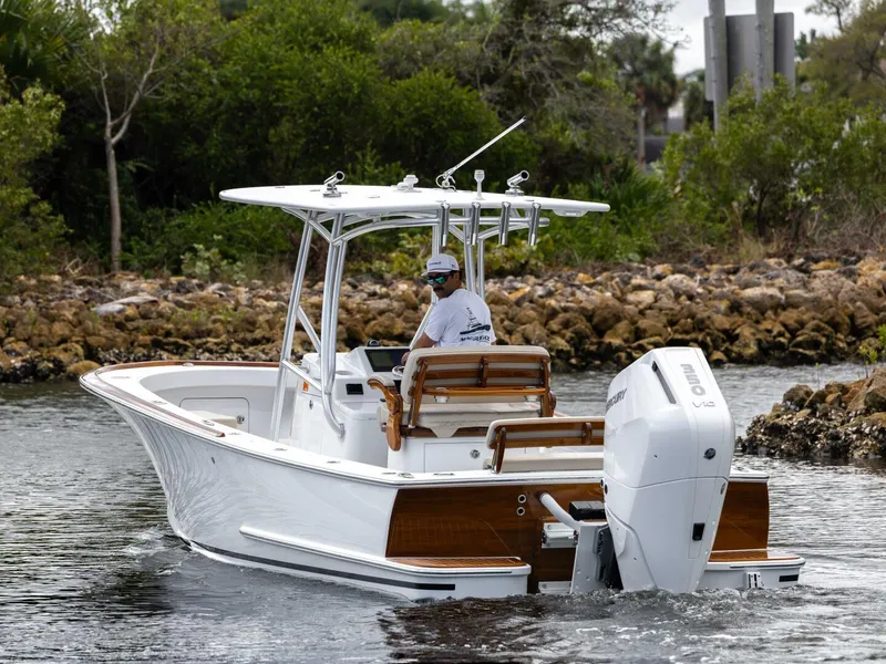 Slide: The Image of 2024 Xcelerator Boatworks 26 cruising on a calm waterway, surrounded by lush greenery. - 6
