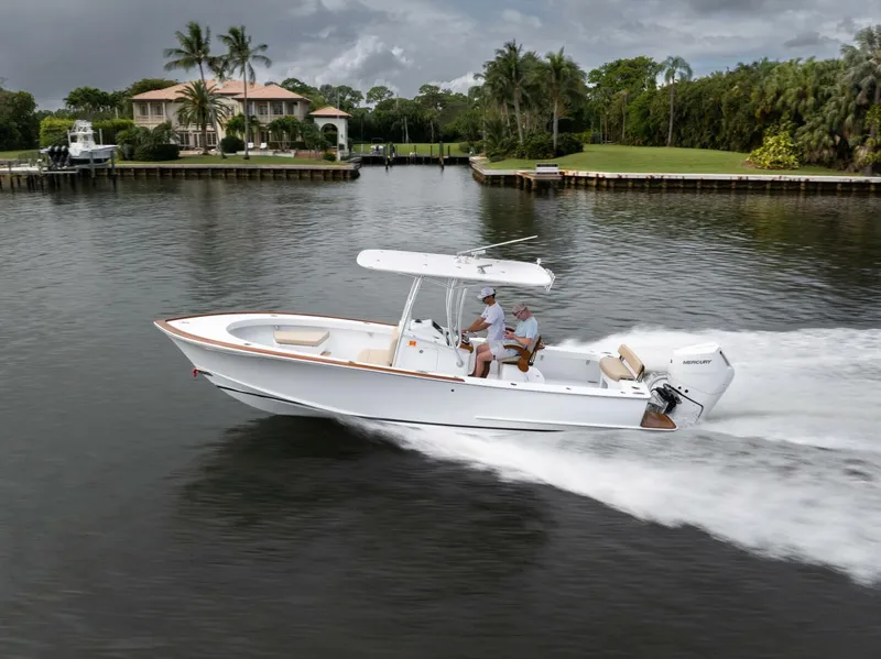 Slide: The Image of 2024 Xcelerator Boatworks 26 cruising on a scenic waterway near luxury homes. - 7
