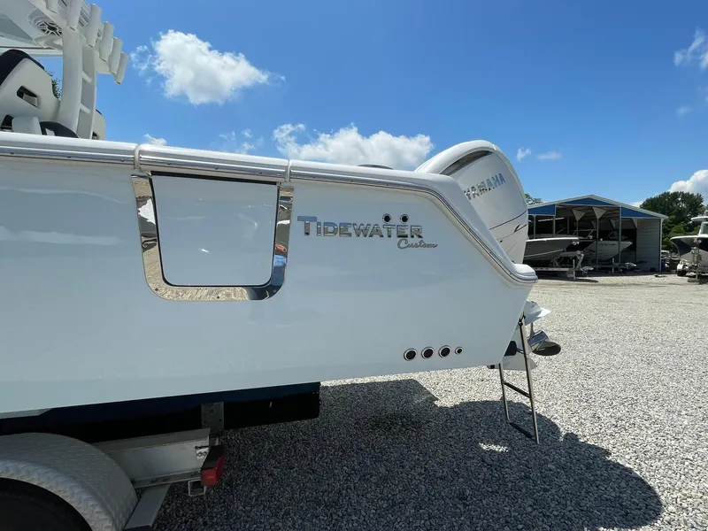 Slide: The Image of 2026 Tidewater 302 CC Adventure boat, rear view, parked on gravel under blue sky. - 3