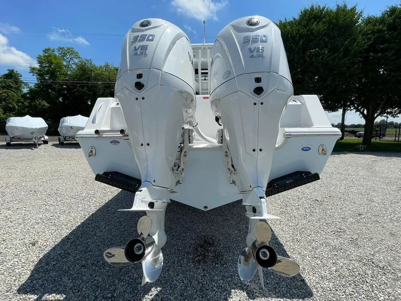 Slide: The Image of 2026 Tidewater 302 CC Adventure boat with dual outboard engines on gravel lot. - 67