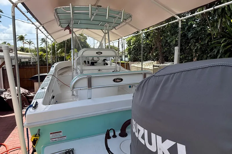 Slide: The Image of 2023 Dusky 252 boat with Suzuki engine, parked under canopy, surrounded by greenery. - 13