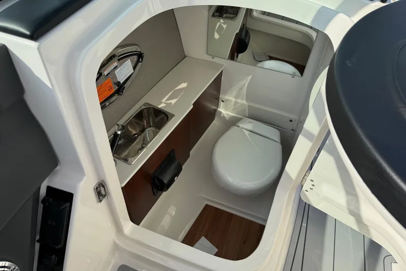 Slide: The Image of 2025 Chaparral 2870 SSX boat interior with compact bathroom, featuring a toilet and sink. - 13