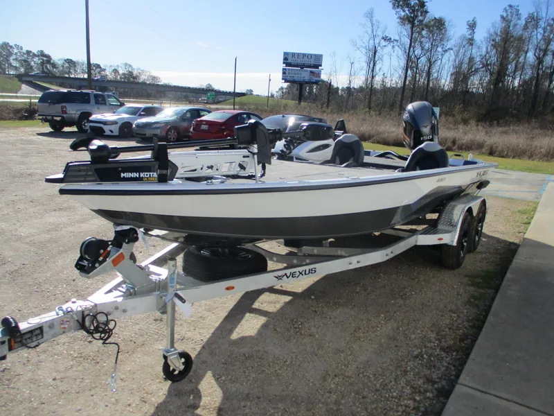 Slide: The Image of 2025 Vexus AVX 1980 boat on trailer, parked outdoors, with Minn Kota motor. - 2