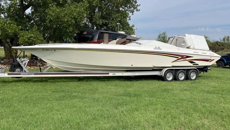 The Image of 1998 Fountain 38 Fever speedboat on trailer, parked on grass, side view. - 0