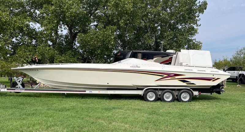 Slide: The Image of 1998 Fountain 38 Fever speedboat on trailer, parked on grass with trees in background. - 1