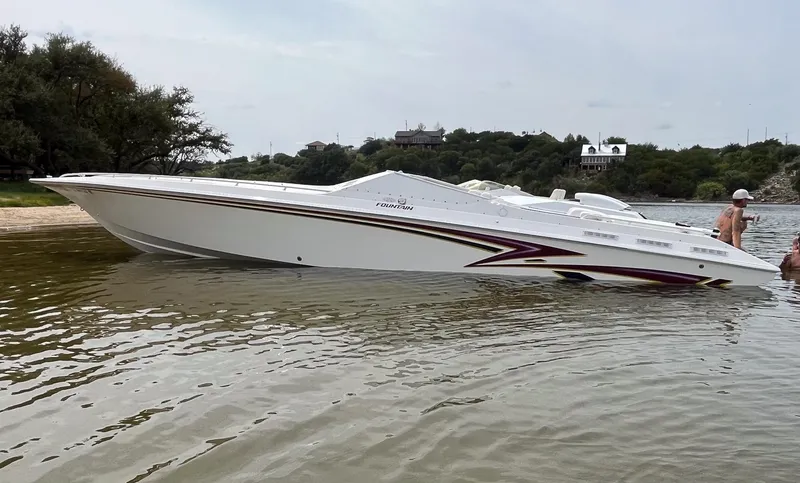 Slide: The Image of 1998 Fountain 38 Fever speedboat in shallow water, featuring sleek white design with maroon accents. - 2