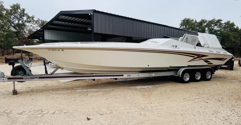 Slide: The Image of 1998 Fountain 38 Fever speedboat on trailer, parked outdoors near a metal shed. - 3