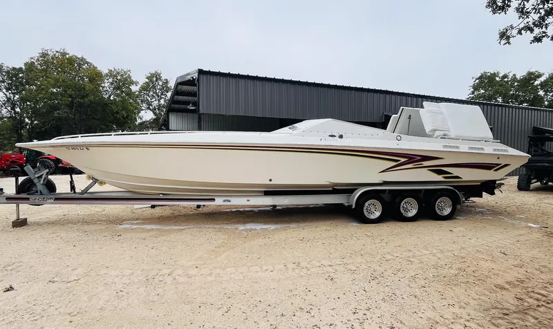 Slide: The Image of 1998 Fountain 38 Fever boat on trailer, parked outdoors near a building. - 4