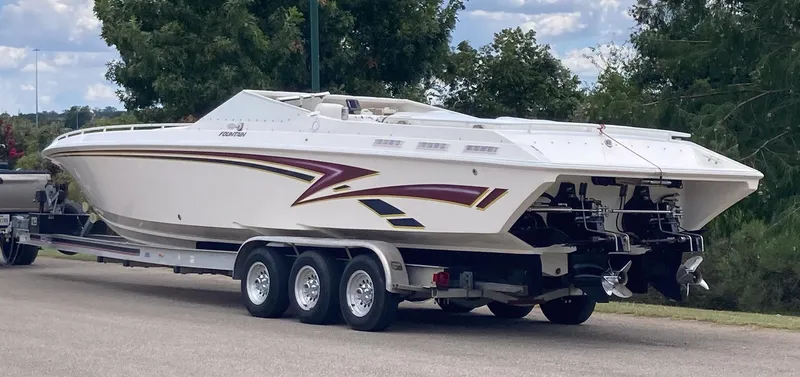Slide: The Image of 1998 Fountain 38 Fever speedboat on trailer, parked outdoors with trees in background. - 5