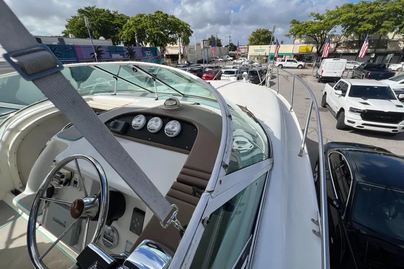 Slide: The Image of 1996 Silverton 310 Express boat dashboard and steering wheel, parked in a busy lot. - 12
