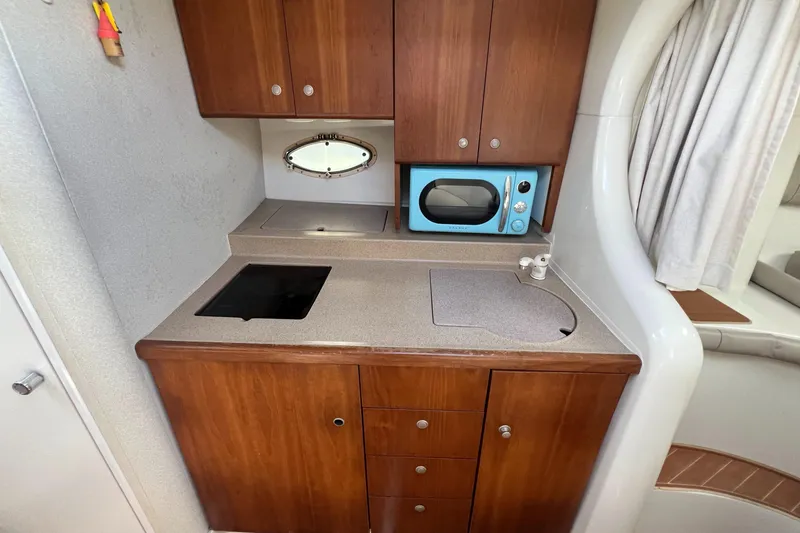 Slide: The Image of 1996 Silverton 310 Express boat kitchen with wooden cabinets and a blue microwave. - 15