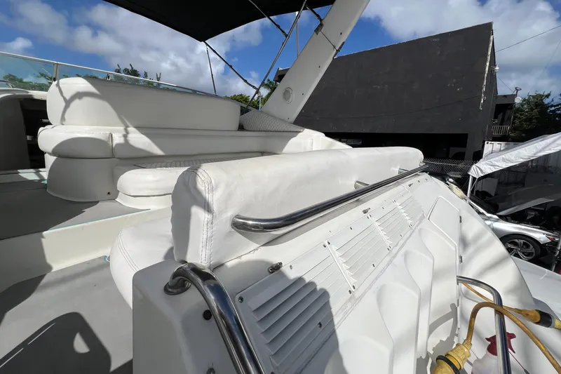 Slide: The Image of 1996 Silverton 310 Express boat interior with white seating and railing under a blue sky. - 36