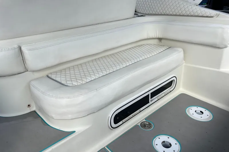 Slide: The Image of 1996 Silverton 310 Express boat interior with white cushioned seating and storage compartment. - 7