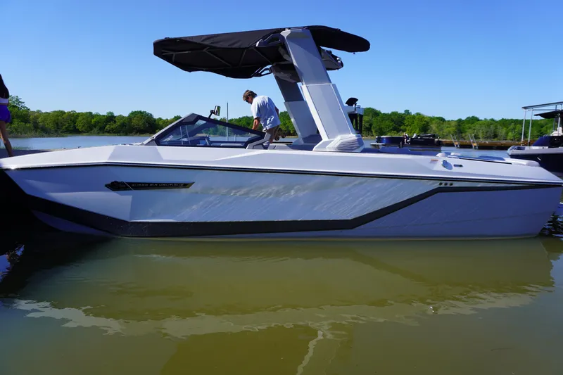 Slide: The Image of 2025 Nautique Super Air Nautique G25 boat on water, sleek design, black canopy. - 2