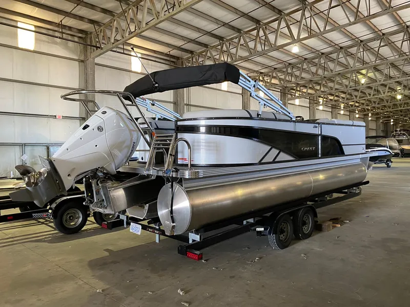 The Image of 2023 Crest Classic DLX 240 pontoon boat in a spacious indoor storage facility. - 0