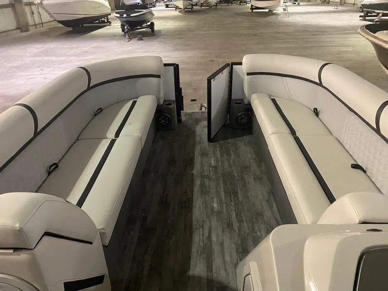 Slide: The Image of 2023 Crest Classic DLX 240 pontoon boat interior with spacious seating in a showroom. - 8