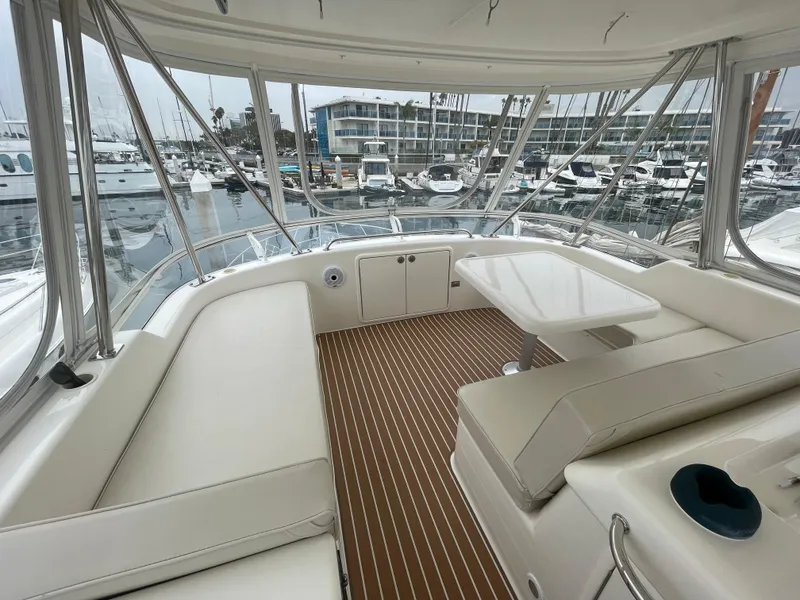 Slide: The Image of 2005 Riviera 47 Open Flybridge Series II interior with marina view, featuring white seating and table. - 17