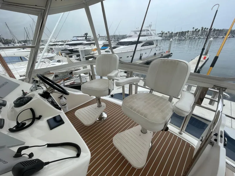 Slide: The Image of 2005 Riviera 47 Open Flybridge Series II, helm view with marina backdrop. - 18