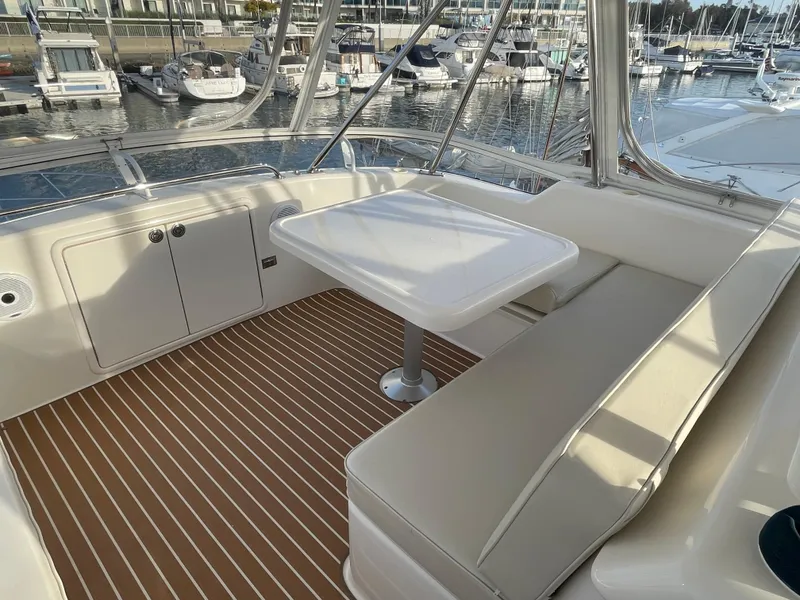 Slide: The Image of 2005 Riviera 47 Open Flybridge Series II yacht interior with seating and table, docked at marina. - 44