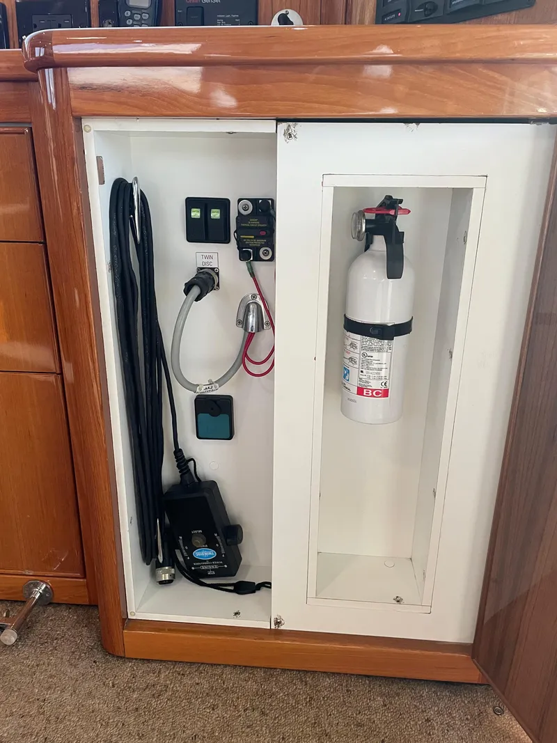 Slide: The Image of 2005 Riviera 47 Open Flybridge Series II interior cabinet with fire extinguisher and electrical components. - 46