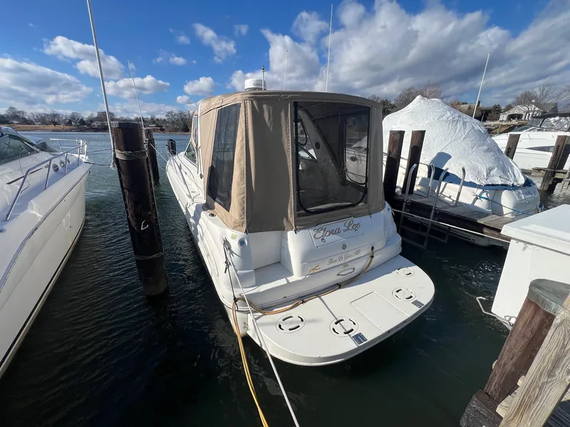 Slide: The Image of 2001 Sea Ray 340 Sundancer docked, featuring a beige canopy and calm waters. - 2