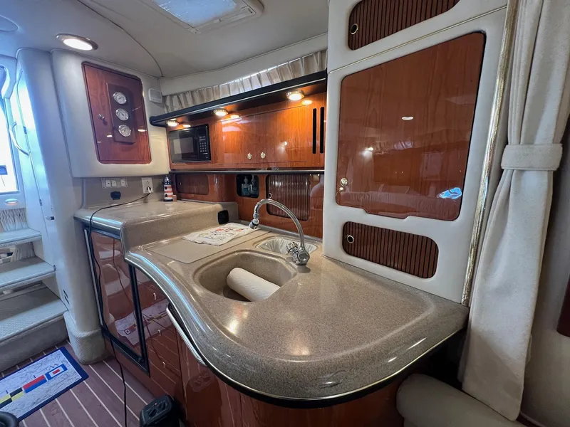 Slide: The Image of 2001 Sea Ray 340 Sundancer interior kitchen with wood cabinets, sink, and microwave. - 25