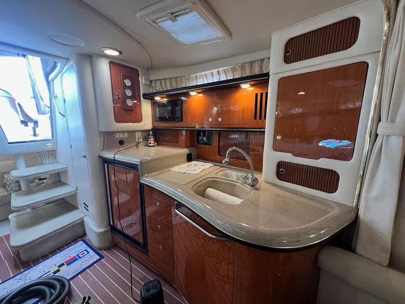 Slide: The Image of 2001 Sea Ray 340 Sundancer interior with kitchenette, featuring wood cabinetry and modern amenities. - 26