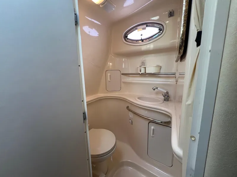Slide: The Image of Compact bathroom in 2001 Sea Ray 340 Sundancer yacht with sink, toilet, and porthole window. - 28