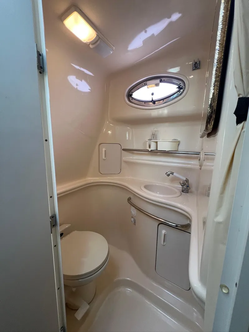 Slide: The Image of 2001 Sea Ray 340 Sundancer bathroom with compact design, featuring toilet, sink, and porthole window. - 29