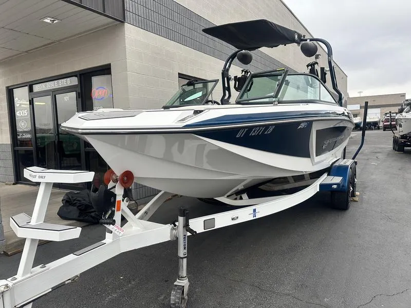 Slide: The Image of 2019 Nautique Super Air Nautique GS22 boat on trailer, parked outside a building. - 3