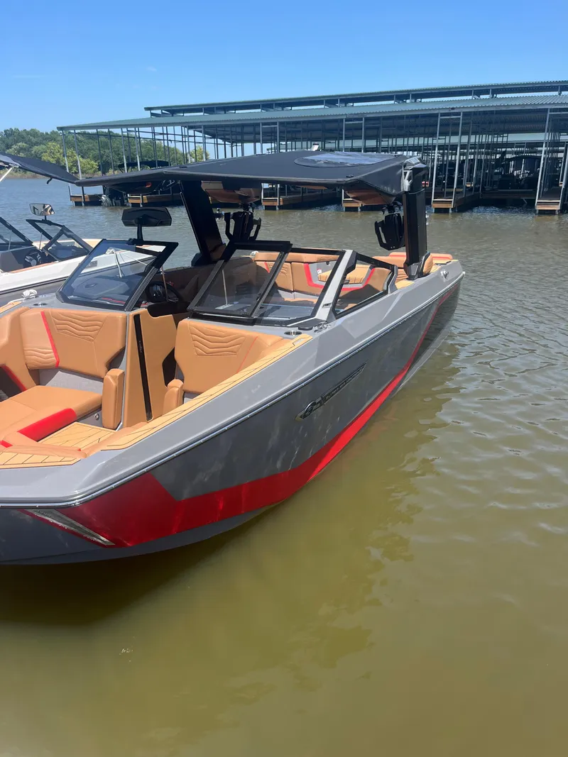 Slide: The Image of 2025 Nautique Super Air Nautique G23 boat with sleek design, docked on calm water. - 6