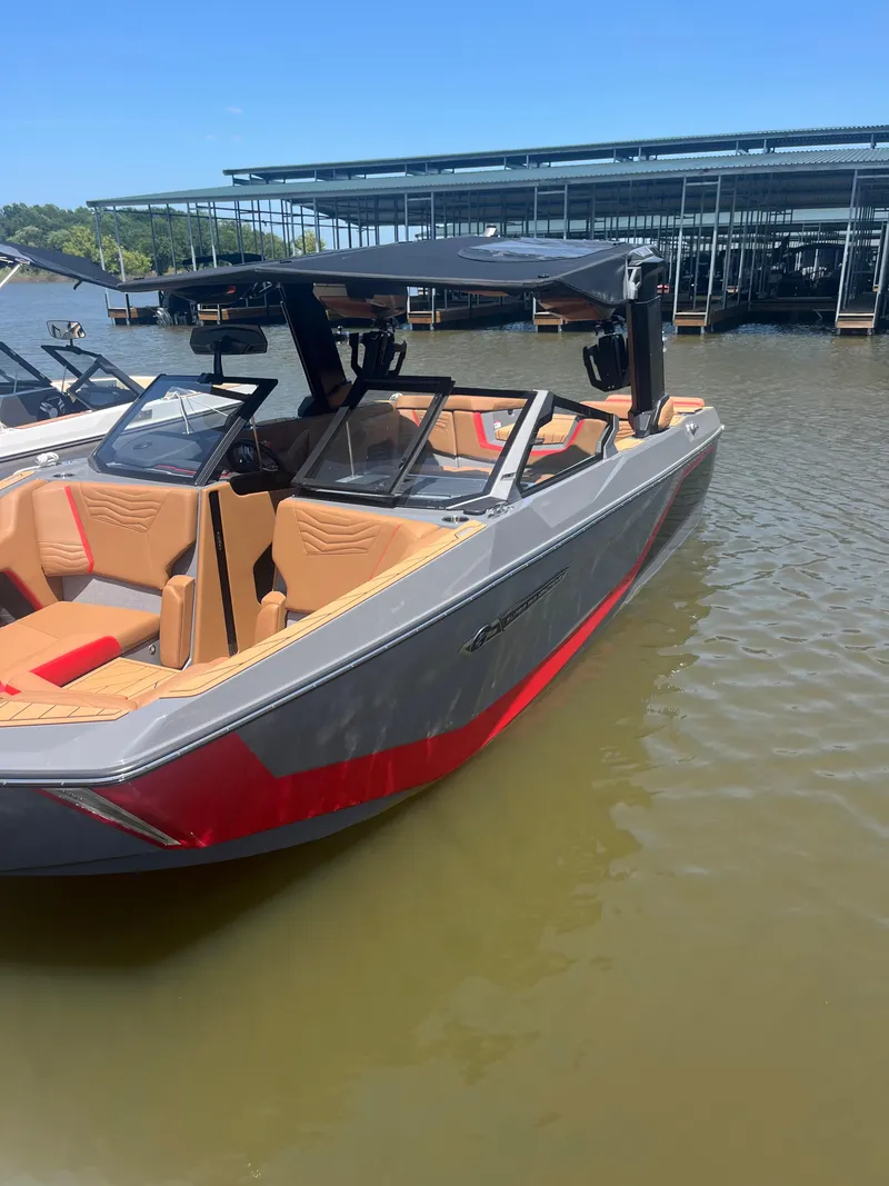 Slide: The Image of 2025 Nautique Super Air Nautique G23 boat with sleek design, docked on calm water. - 8
