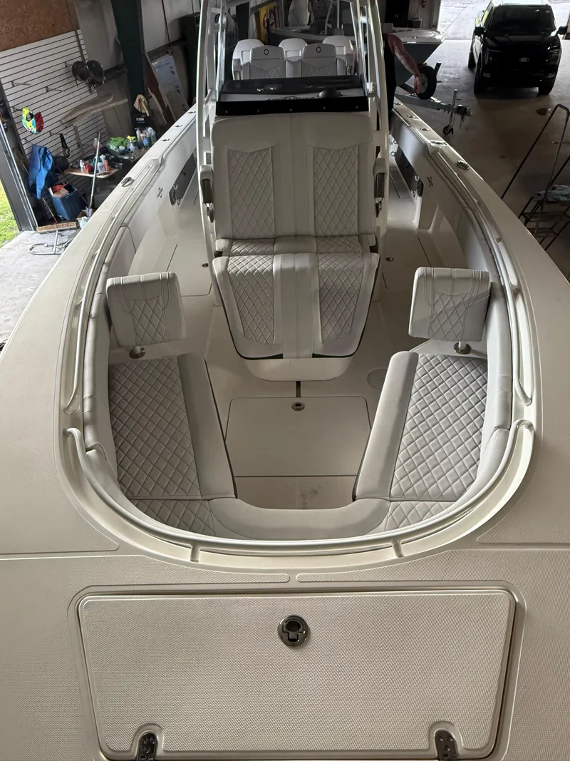 Slide: The Image of 2023 Fountain 34 CC boat interior with white cushioned seating in a garage. - 15