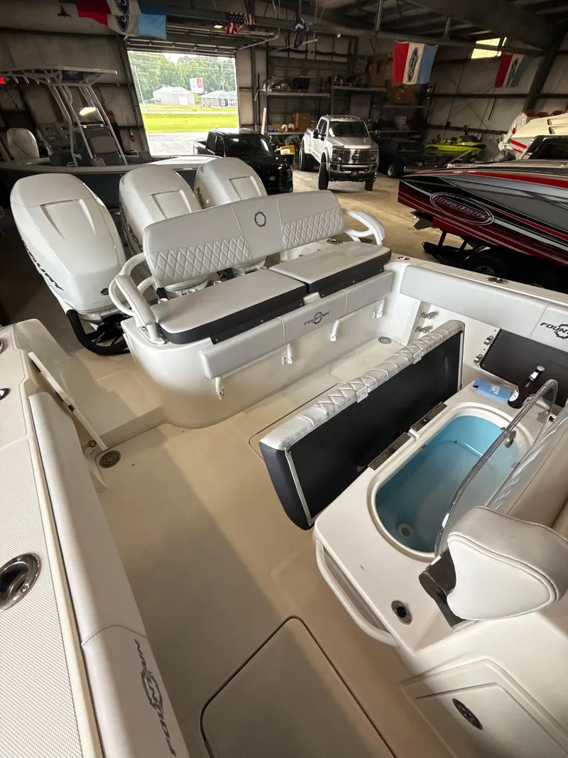 Slide: The Image of 2023 Fountain 34 CC boat interior with seating and storage compartments in a garage setting. - 16