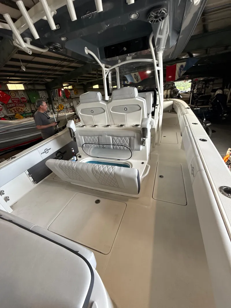 Slide: The Image of 2023 Fountain 34 CC boat interior with seating and storage in a garage setting. - 20