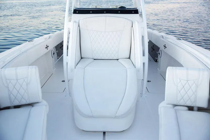 Slide: The Image of 2024 Fountain 34 CC boat interior with white cushioned seating on calm water. - 7