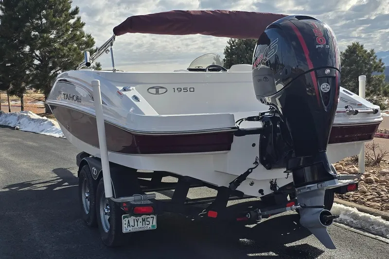 Slide: The Image of 2020 Tahoe 1950 boat with outboard motor on trailer, parked outdoors. - 4