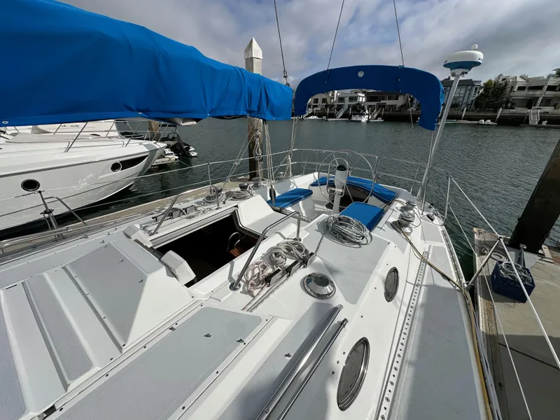 Slide: The Image of 1987 Hunter Legend 45 sailboat docked, featuring blue canopy and sleek deck design. - 16