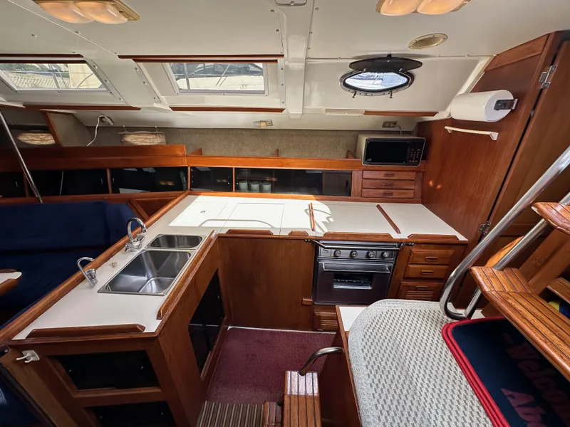 Slide: The Image of Interior of 1987 Hunter Legend 45 sailboat, featuring a compact kitchen with wood cabinetry. - 29