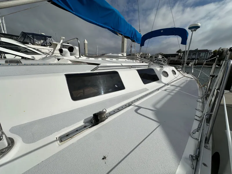 Slide: The Image of 1987 Hunter Legend 45 sailboat with blue canopy, docked at marina under cloudy sky. - 7