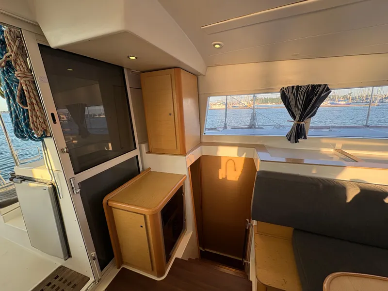 Slide: The Image of Interior of 2012 Lagoon 400 catamaran with seating, window view, and wooden cabinetry. - 12