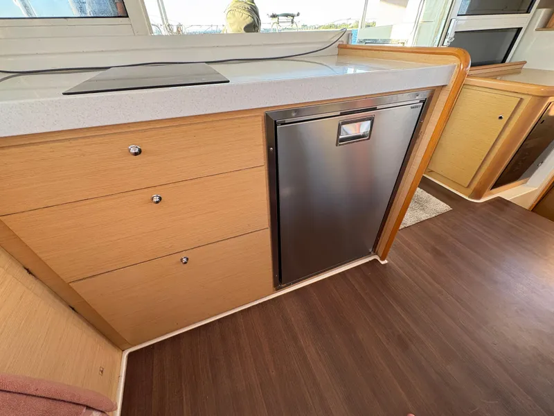 Slide: The Image of Modern kitchen area in a 2012 Lagoon 400 yacht with wood cabinetry and stainless steel fridge. - 41