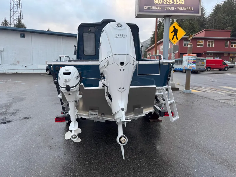 Slide: The Image of 2025 Hewescraft 220 Ocean Pro boat with dual outboard motors, parked on wet pavement. - 4